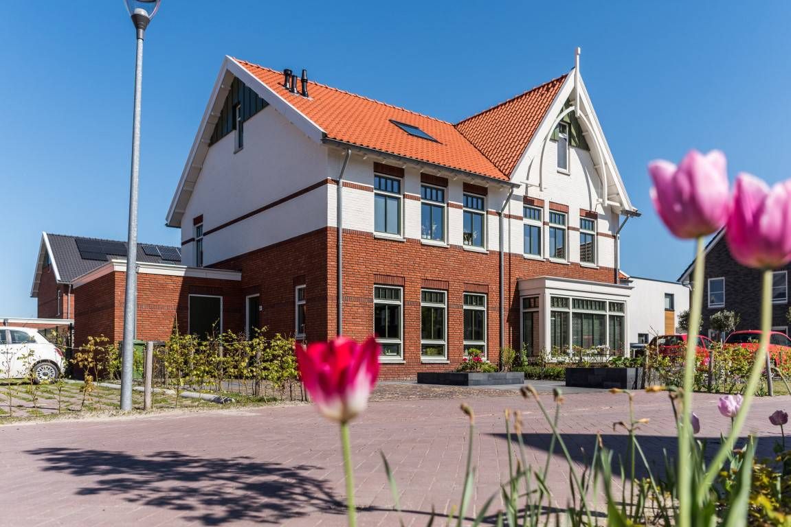 Huis met wit en oranje met bloemen op de foto