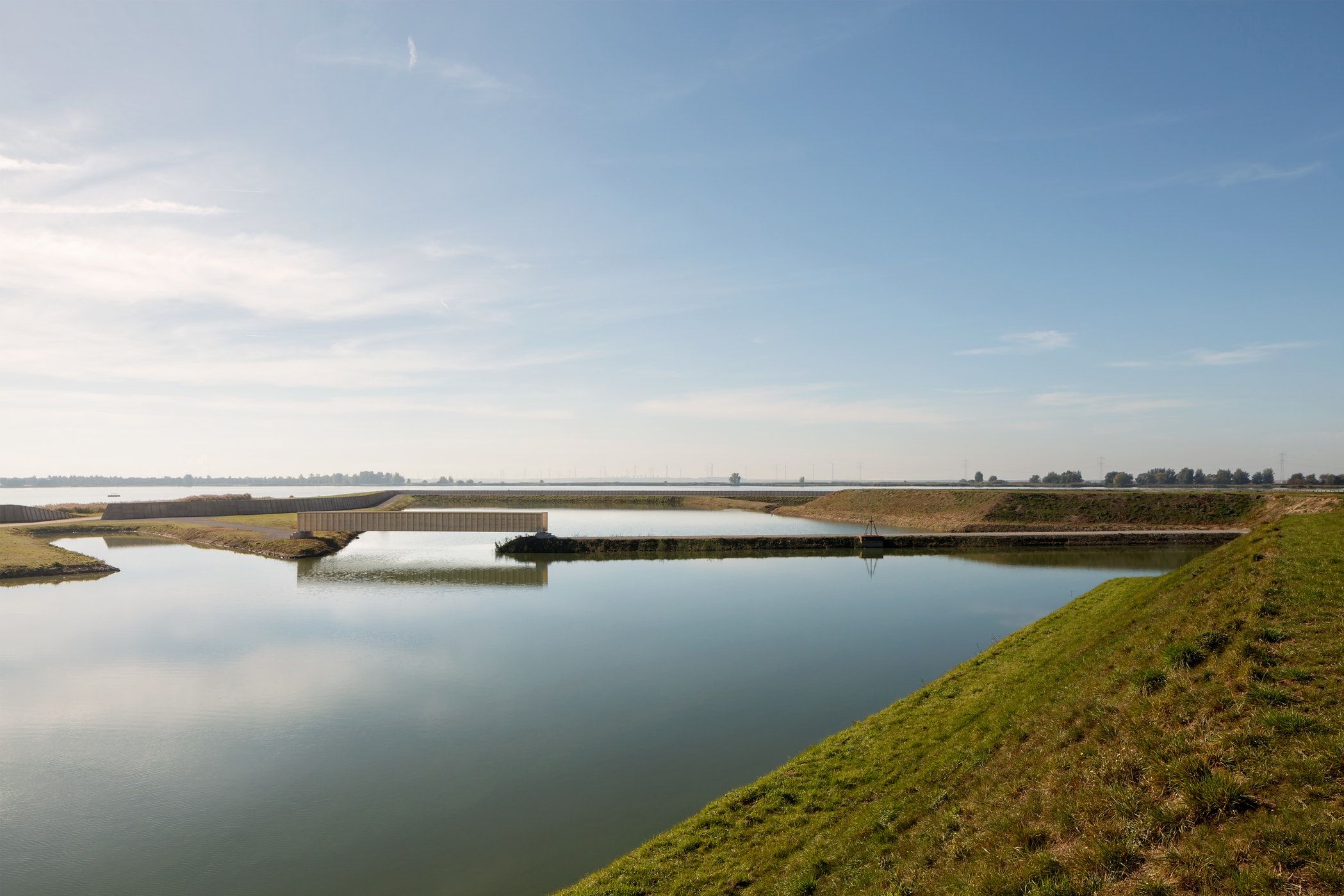 De houten Accoya brug in Bergen Op Zoom met gras en water ervoor van veraf