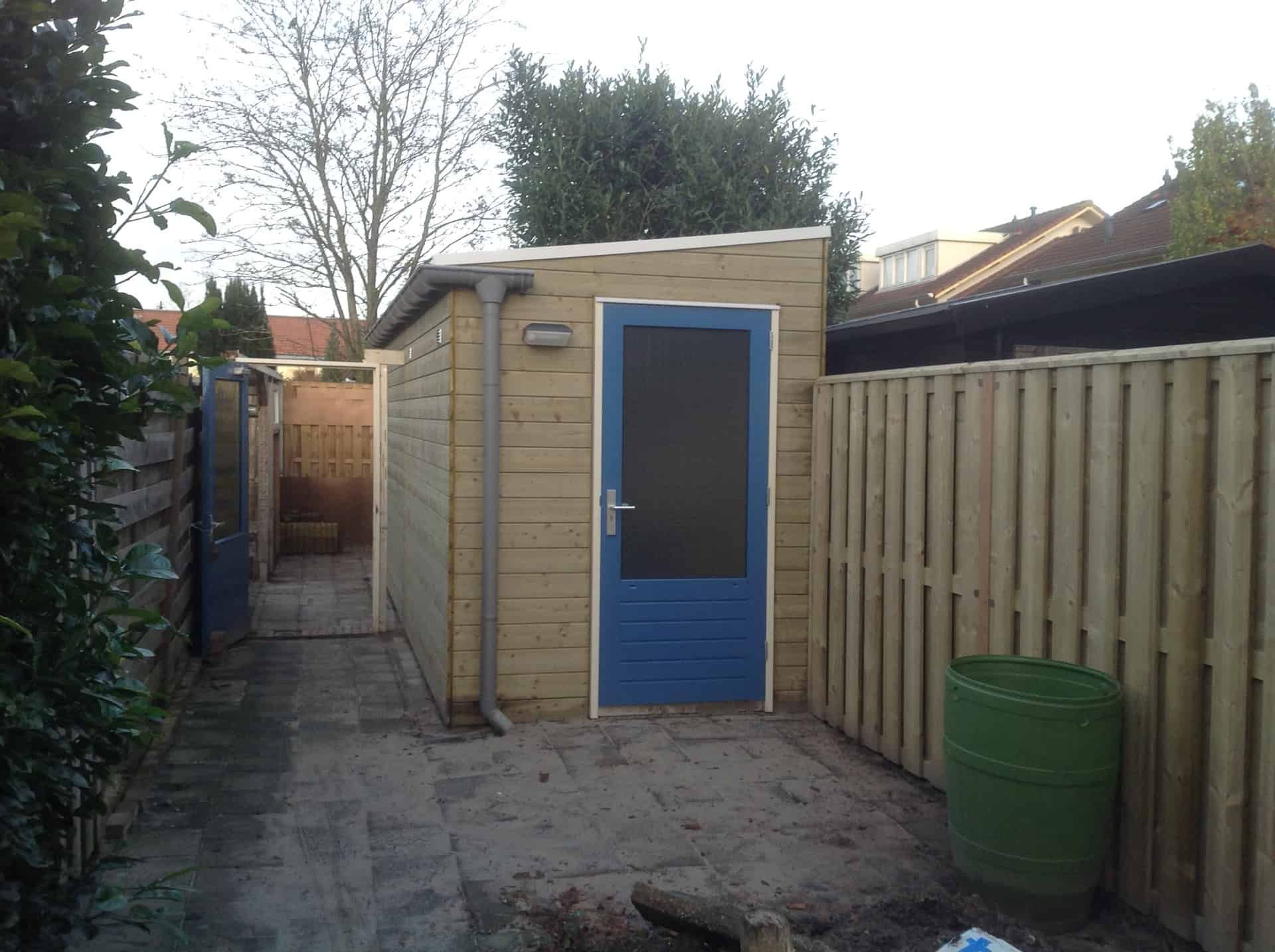 Berging houtkleur met blauwe deur in achtertuin