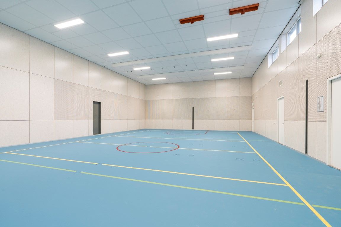De gymzaal van de Brede school in Scheemda met houten wanden en een blauwe vloer