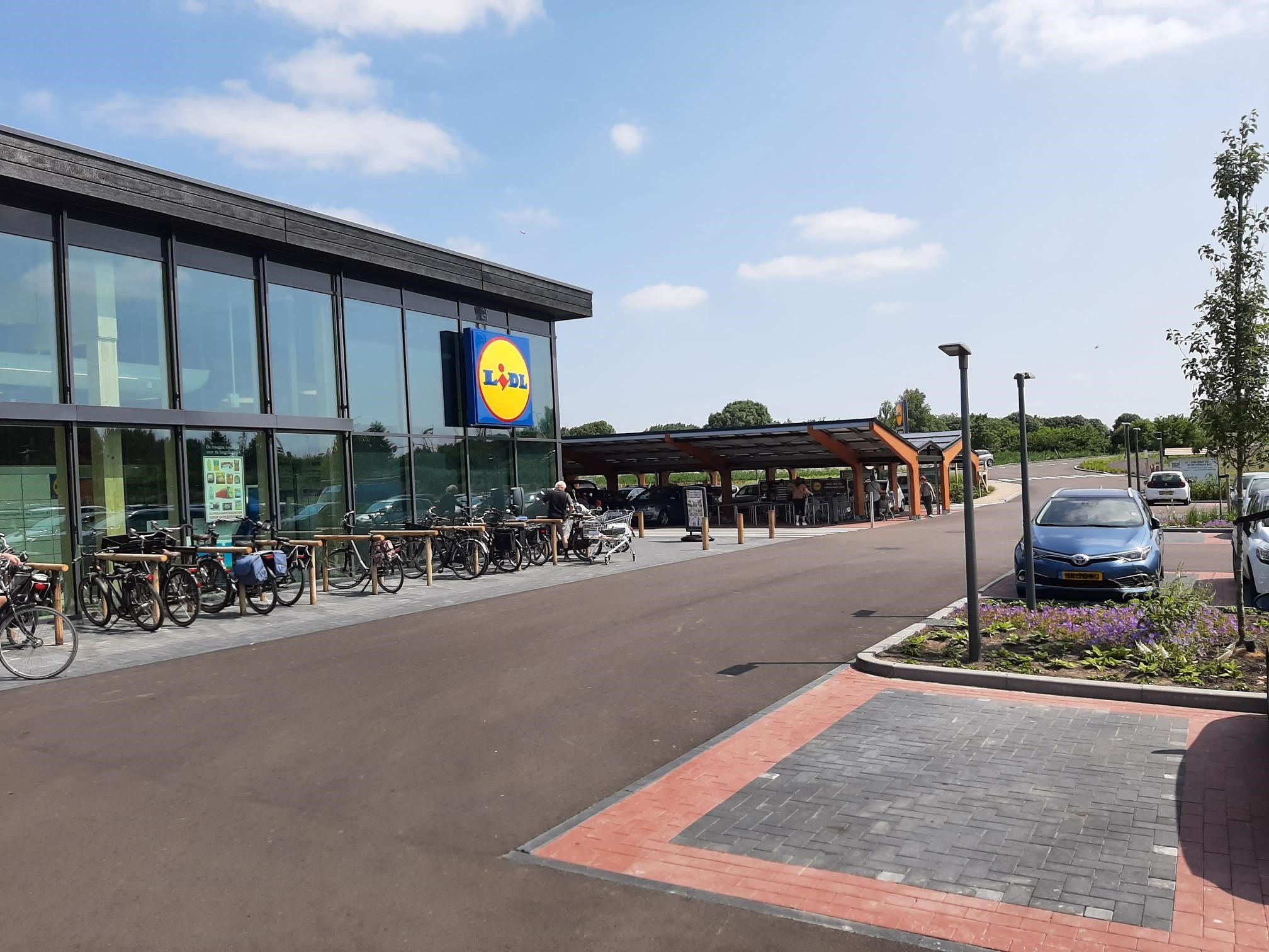 Glazen gebouw van de Lidl met parkeerplaats ervoor