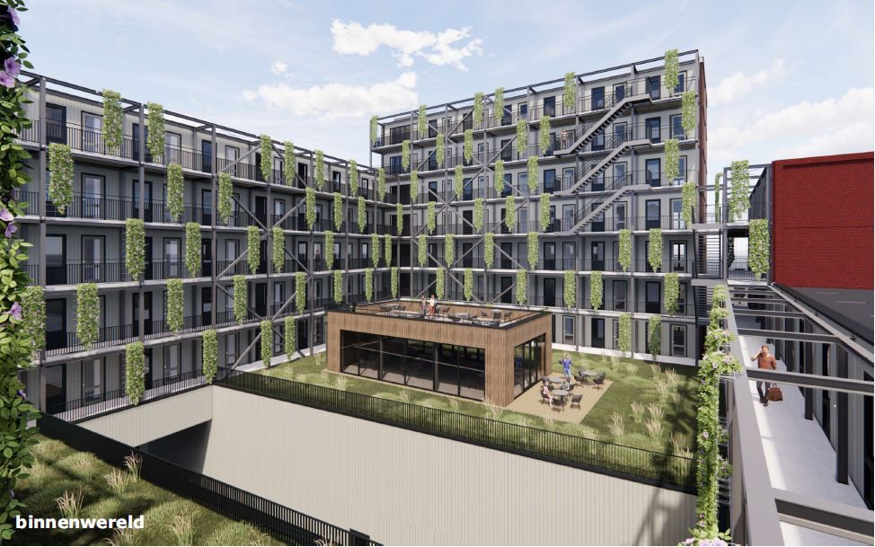Een binnenplaats met veel groen en in het midden een houten vierkant gebouw