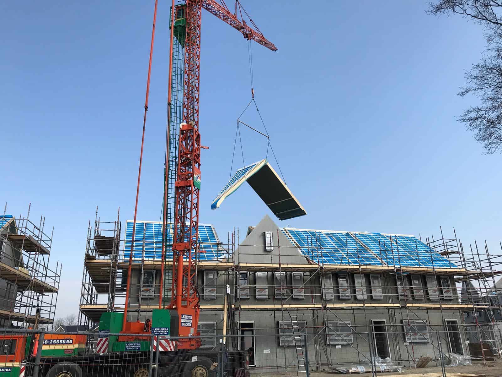 Huizen in de bouw met dak die wordt gehezen door kraan