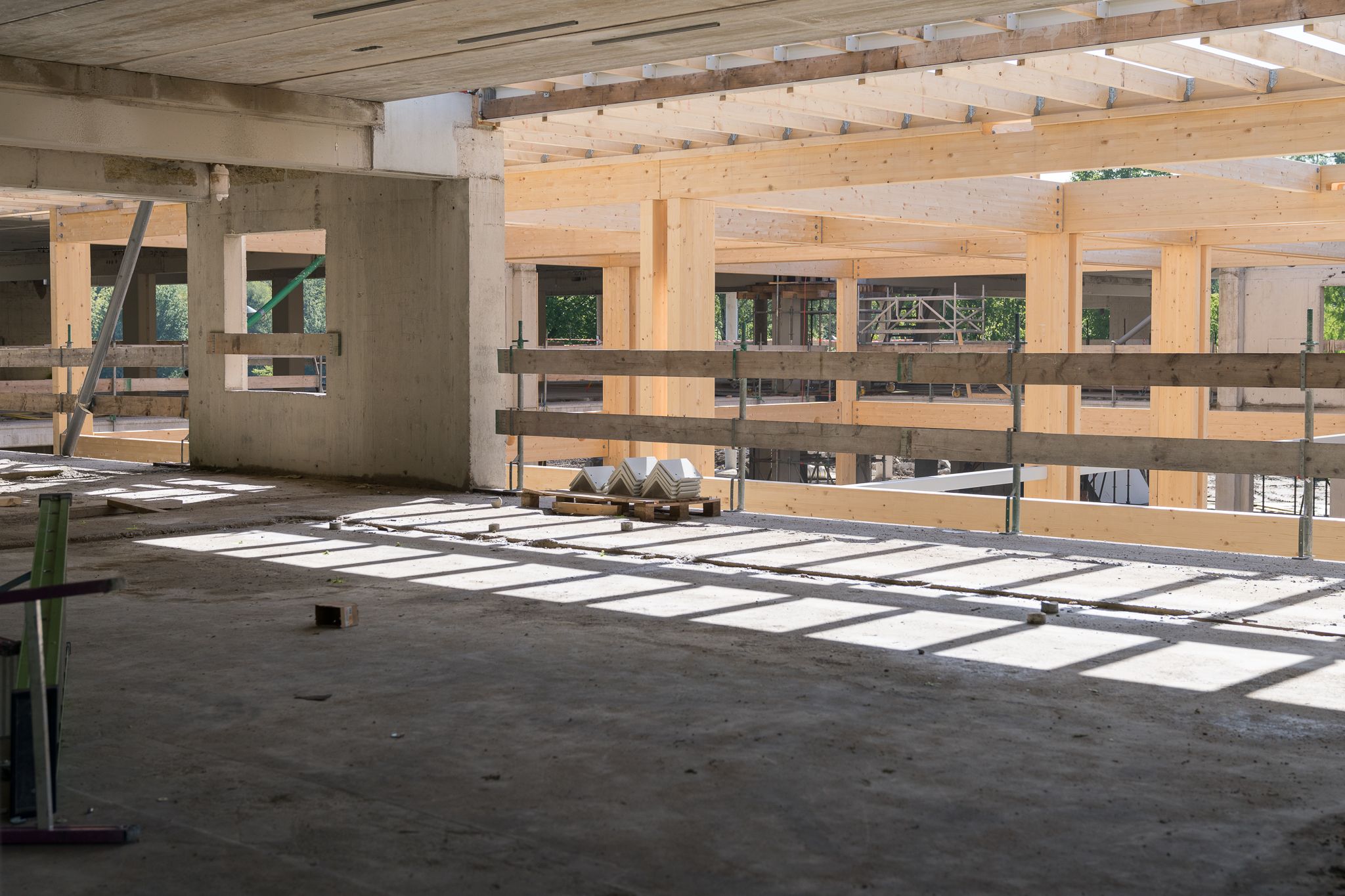 Gebouw in aanbouw met houten balken en een betonnen vloer
