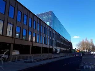 Gebouw met veel ramen en glas en onderaan parkeerplekken