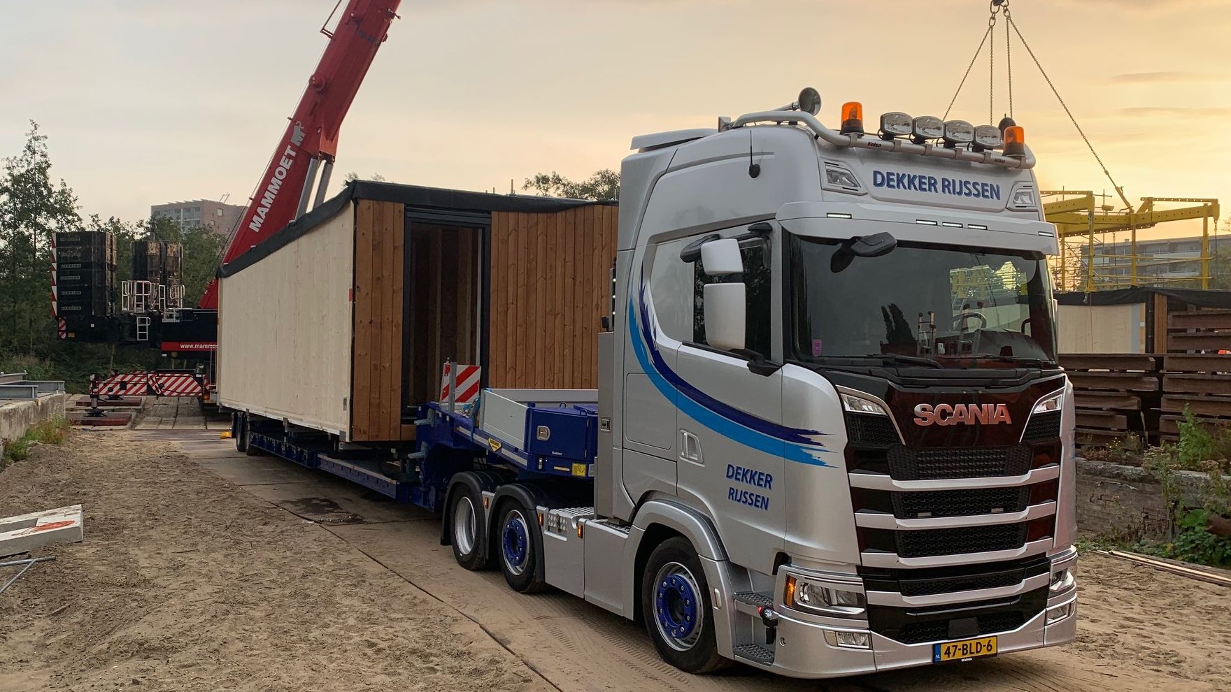 Een houten woonmodule op een vrachtwagen op een bouwplaats