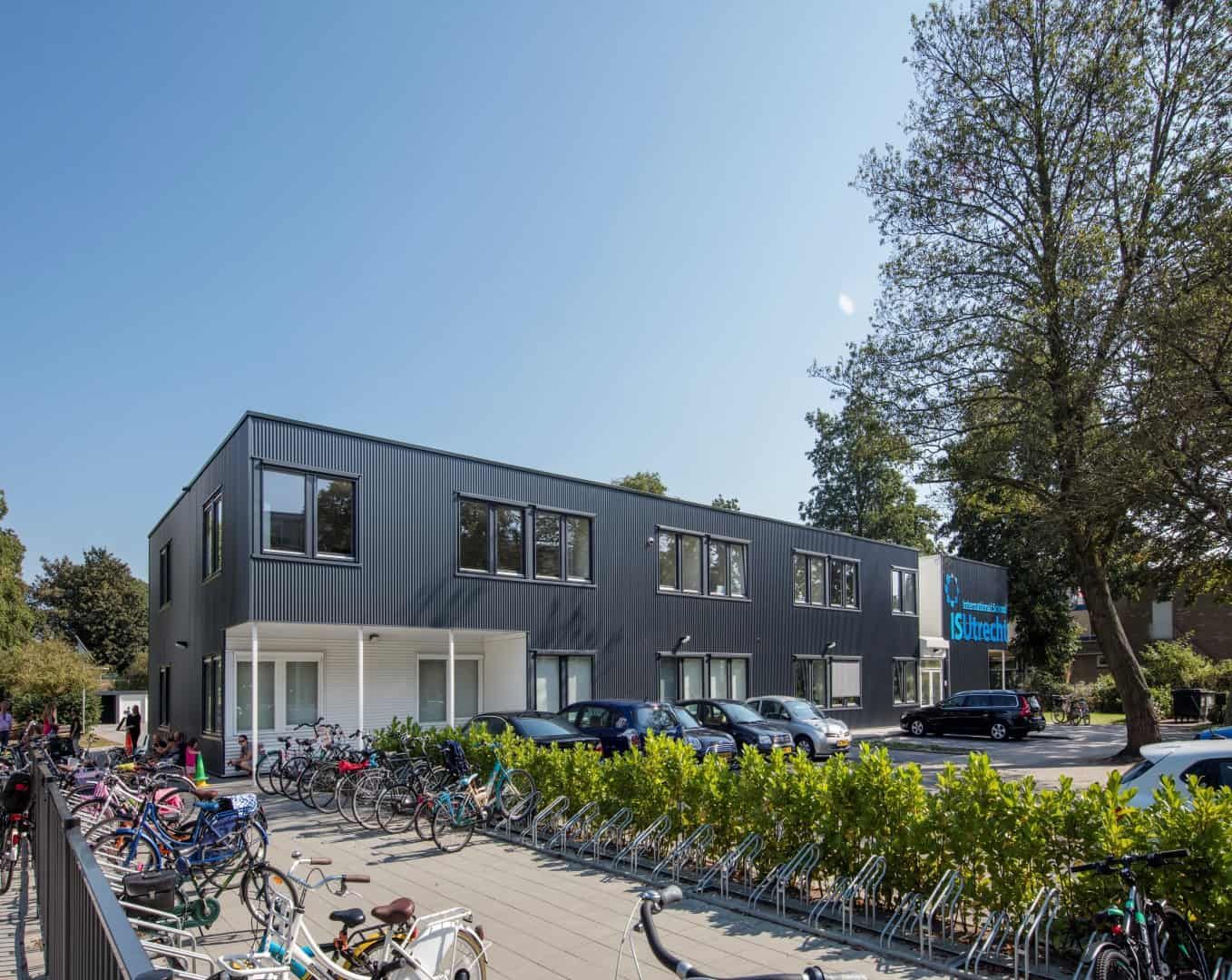 De voorkant met fietsenstalling van de zwarte school te Utrecht met witte ingang