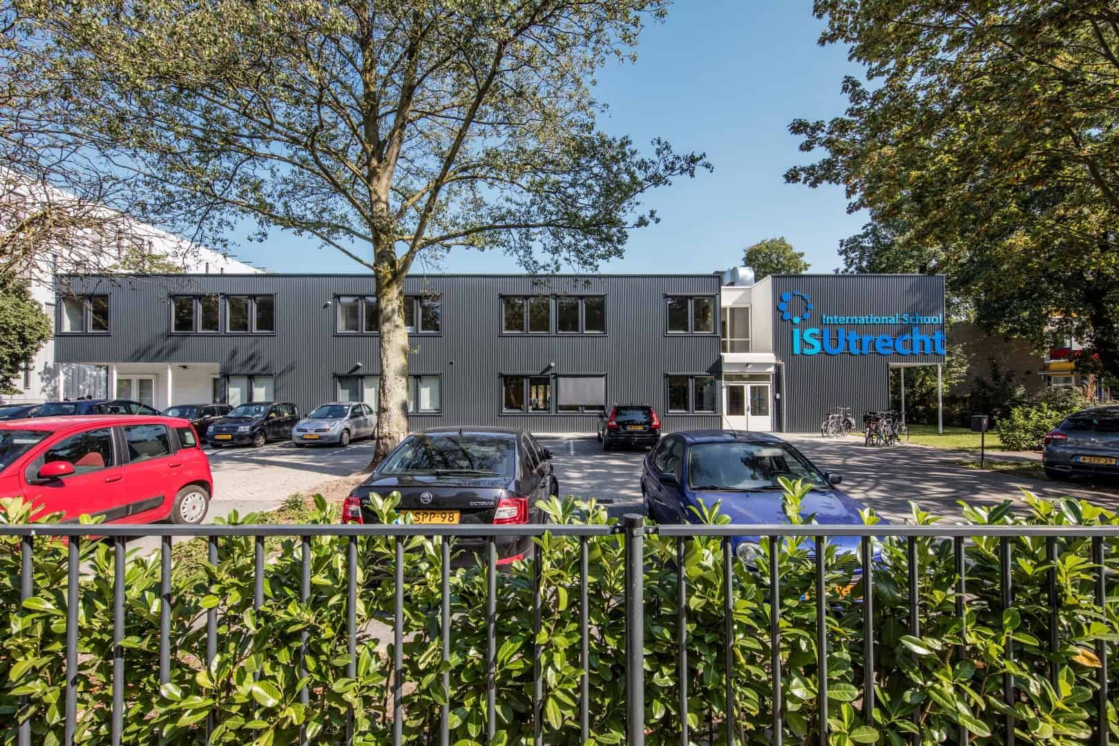 De voorkant van de Internationale school vanaf de straatkant met parkeerplaats ervoor.