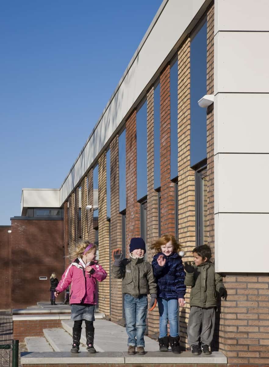 Gebouw van baksteen en kunststof met kinderen op de trap