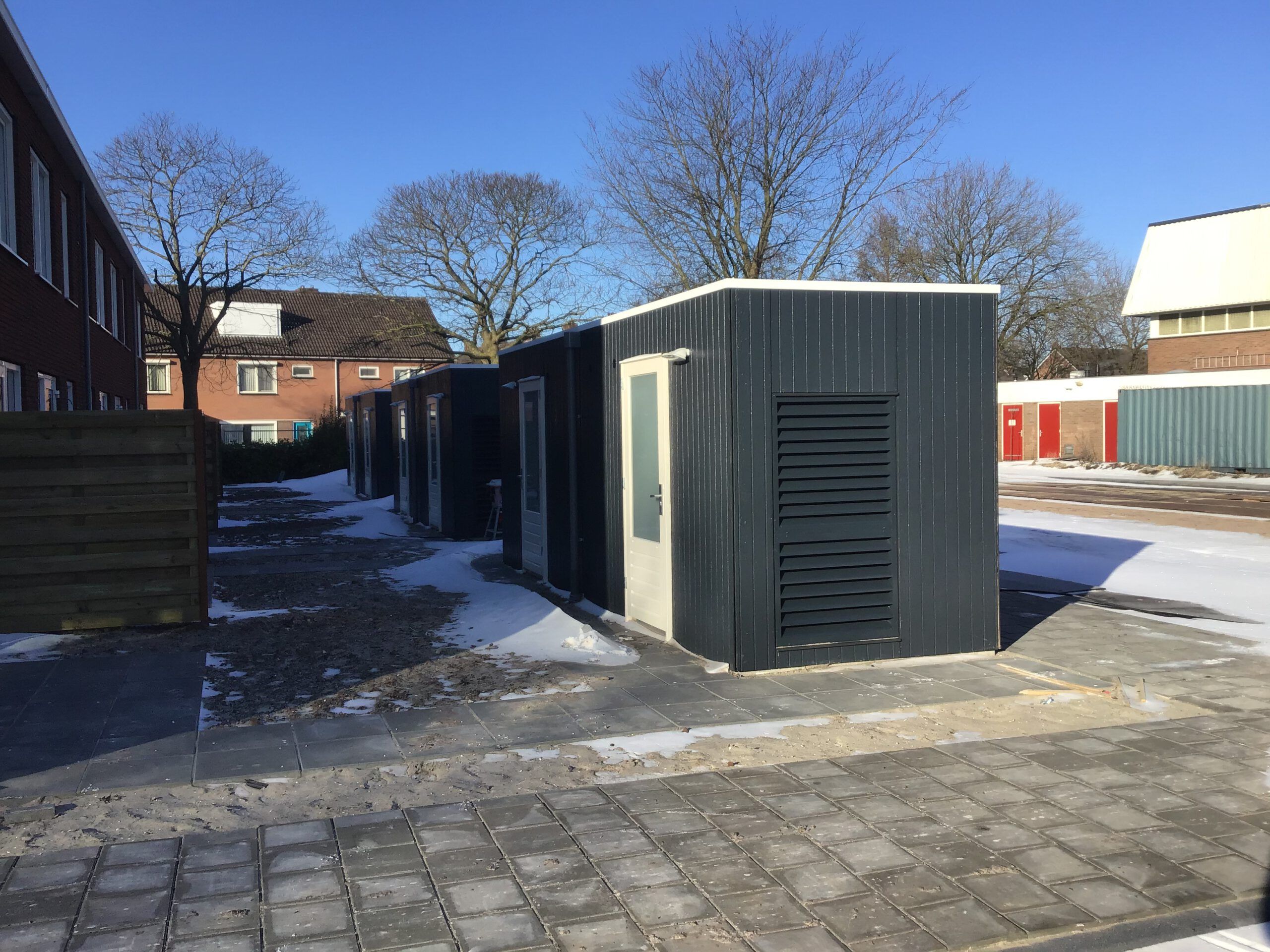 Houten, zwarte schuurtjes achter elkaar met witte deuren