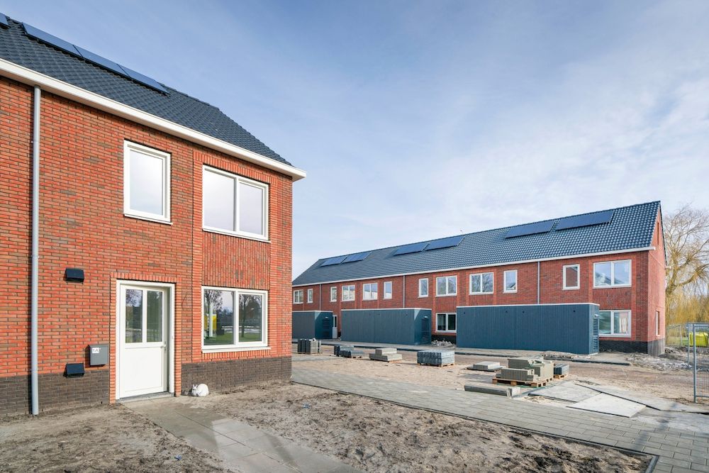 Een wijk in aanbouw met rijtjeshuizen en grijze houten schuurtjes