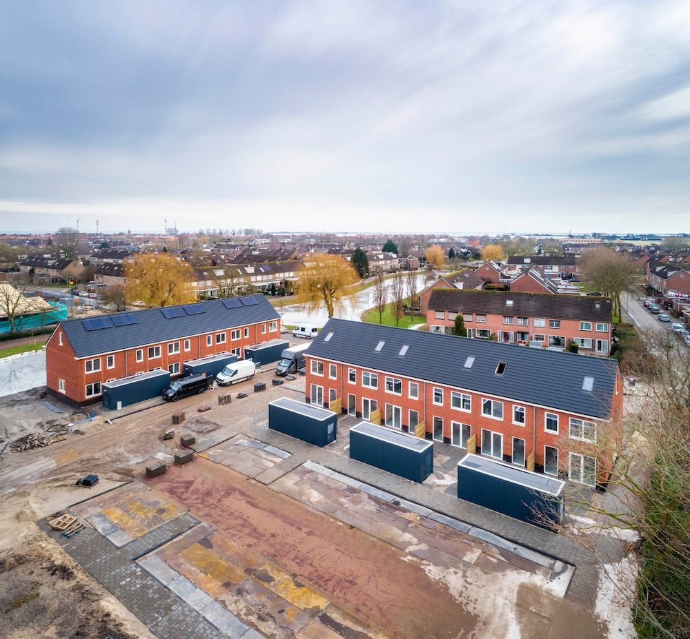 Rijtjeshuizen in een nieuwbouwwijk in aanbouw met grijze schuurtjes