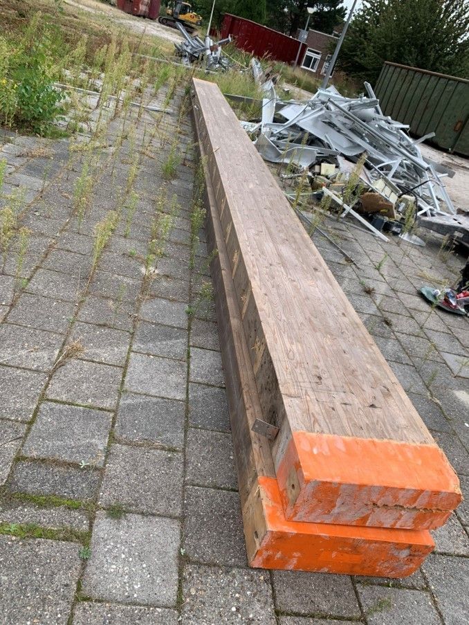 Twee houten balken op elkaar met oranje uiteinden op stoeptegels