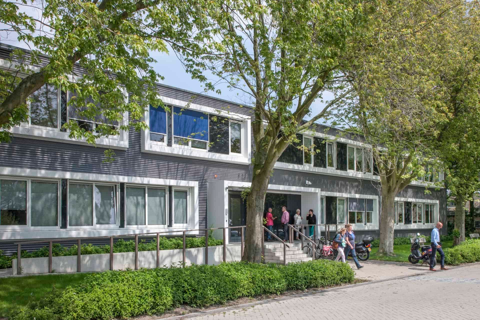 De ingang van het tijdelijke gemeentehuis in Middelharnis met bomen en groen ervoor