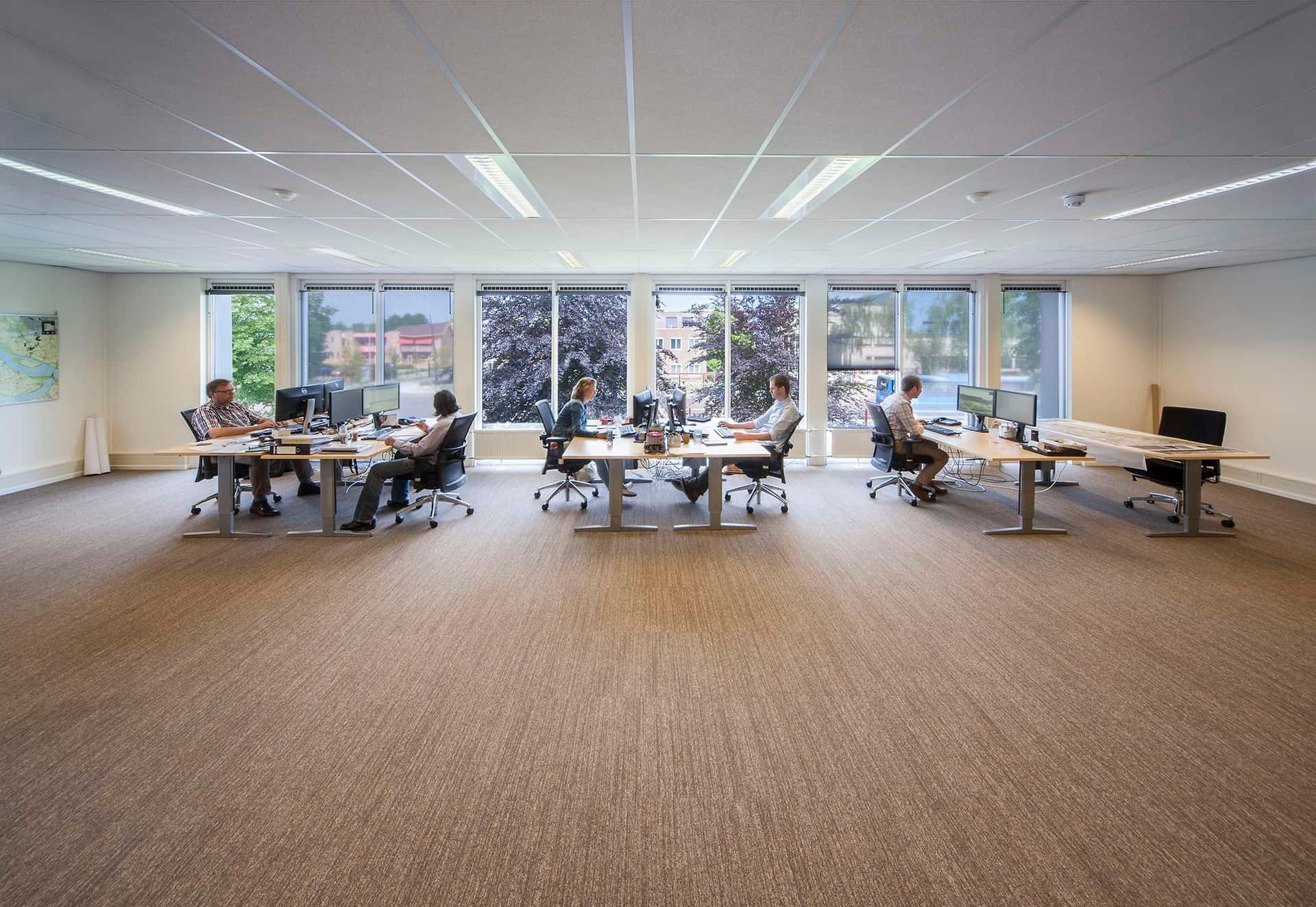 Het kantoor met bureau's , bureaustoelen, computers en grote ramen in het tijdelijke gemeentehuis Middelharnis