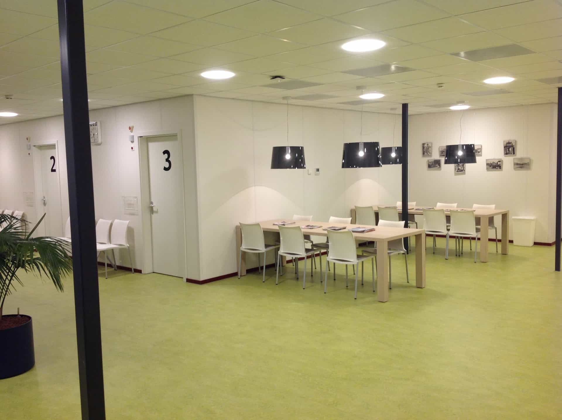 De wachtkamer met een groene vloer en licht meubilair van de poli UMCG