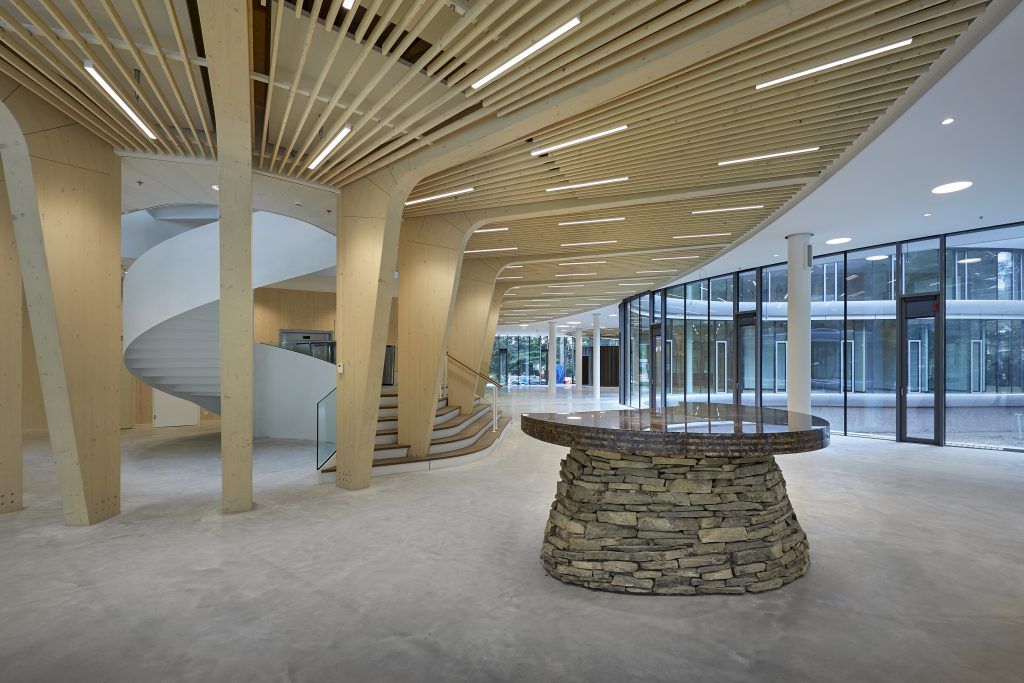 Gelijmde houtconstructies in het interieur van de Triodos bank in Driebergen met stenen tafel in het midden.