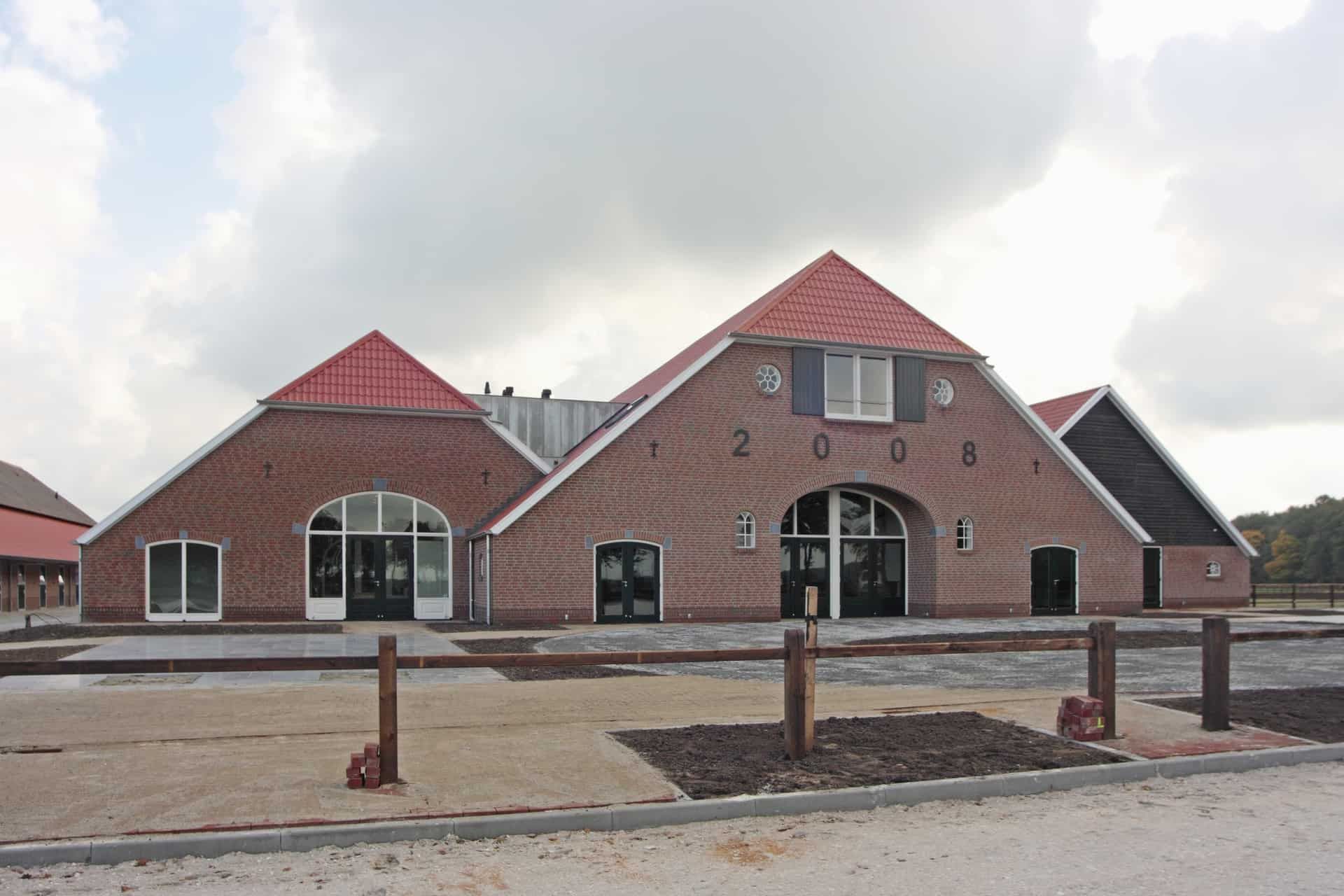 Stoeterij in stegeren met driehoek vormige luxe gebouwen met rijbak met wit zand