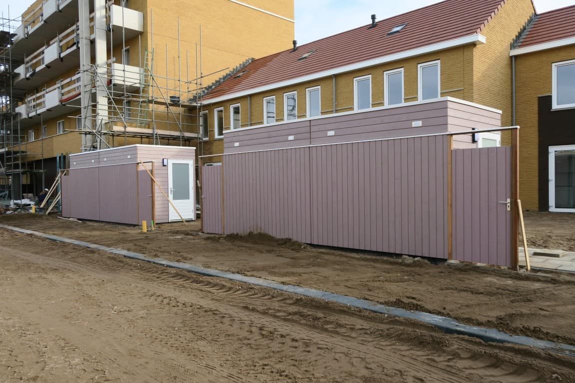 Achterkant van een schuur in aanbouw met zand ervoor