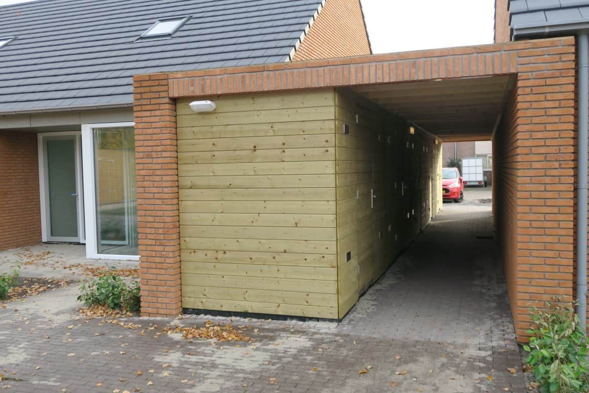 Schuur van hout met een overkapping en doorgang van bakstenen naar de straat