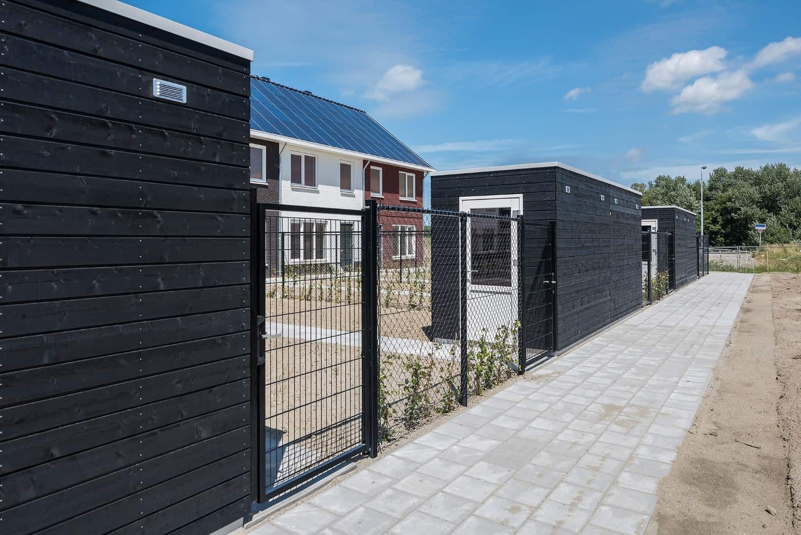 Zwarte schuurtjes in achtertuin me een zwart hek ertussen