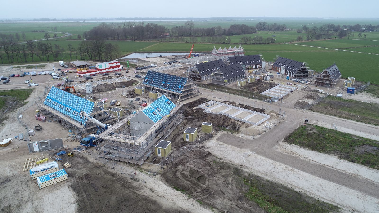 Zijaanzicht van drone foto van bouwplaats waar blauwe prefab daken zijn geplaatst
