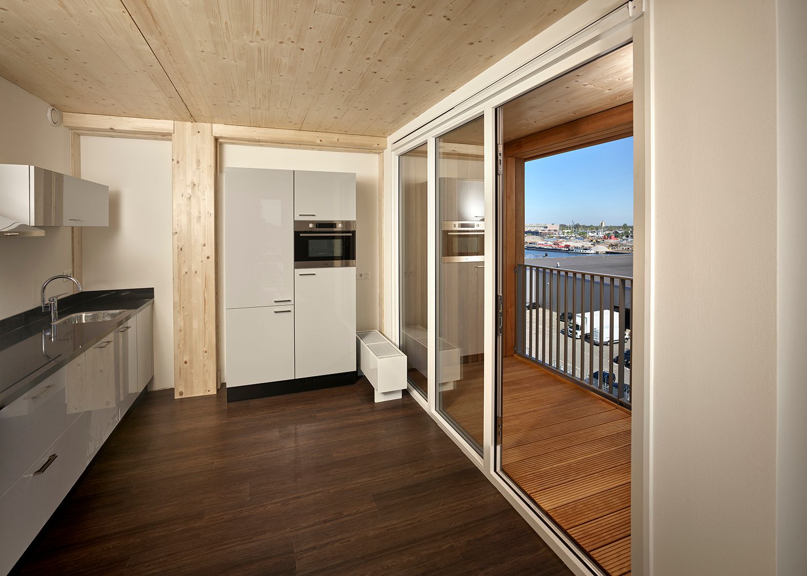 Keuken in een hoog appartement met witte keuken en bruine houten vloer