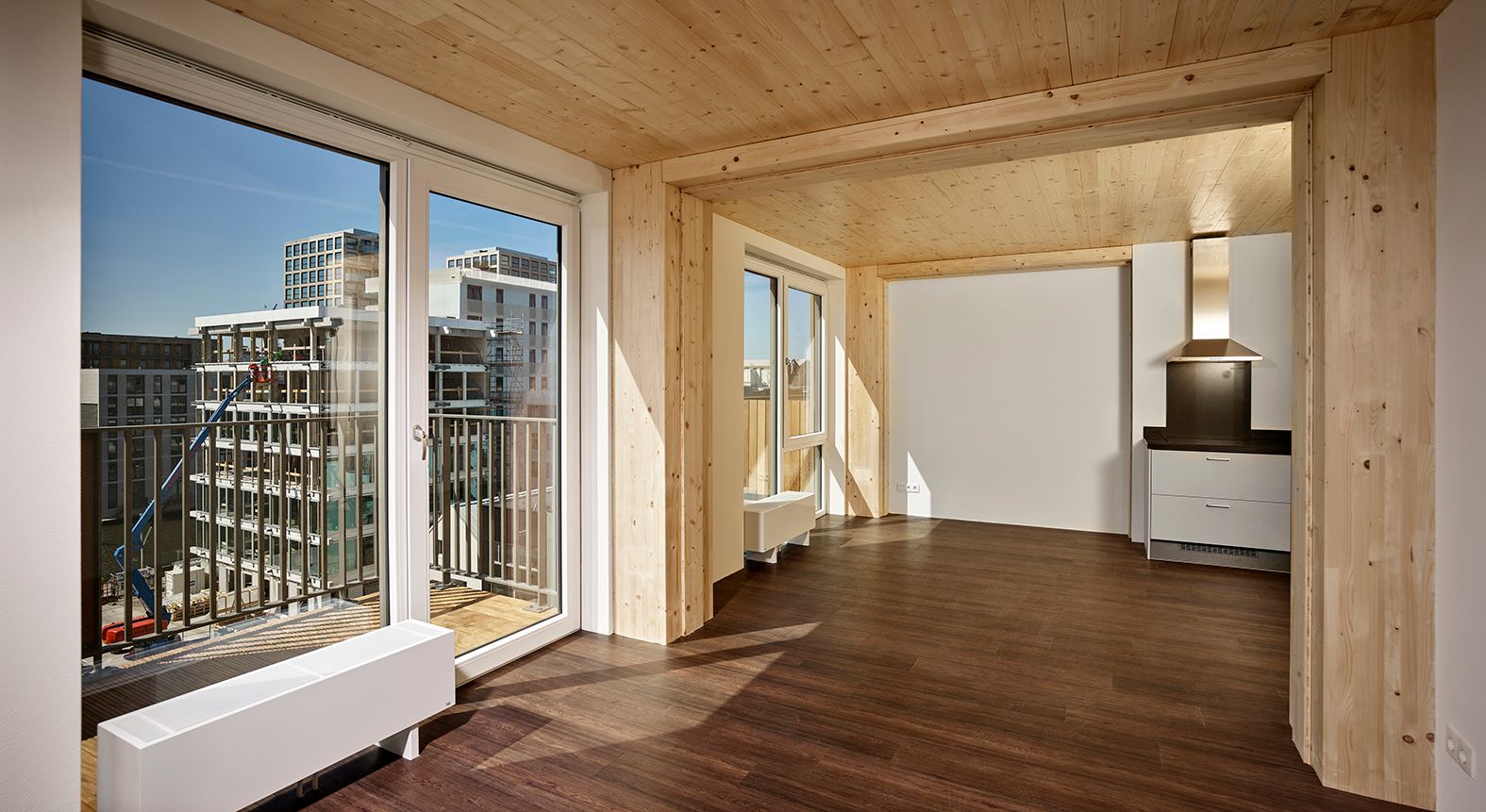 Hoog appartement met donkerbruine houten vloer en grote glazen ramen