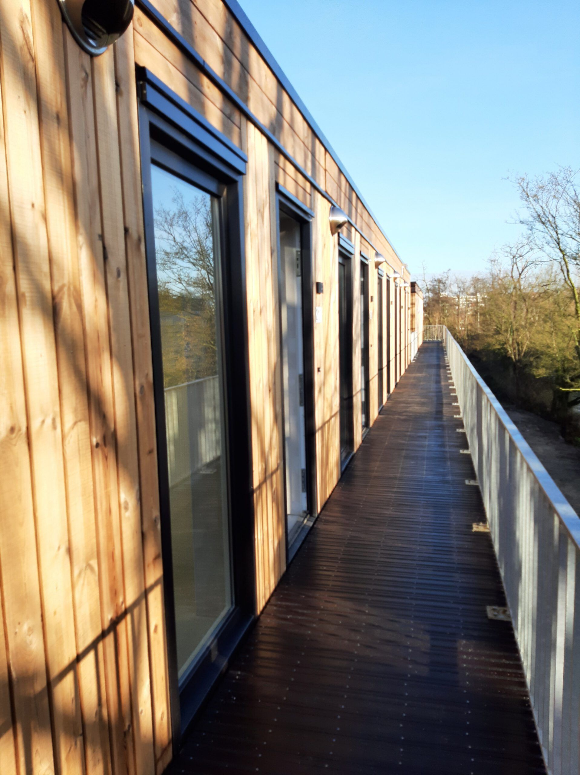 Een gang in de buitenlucht van appartementen van hout