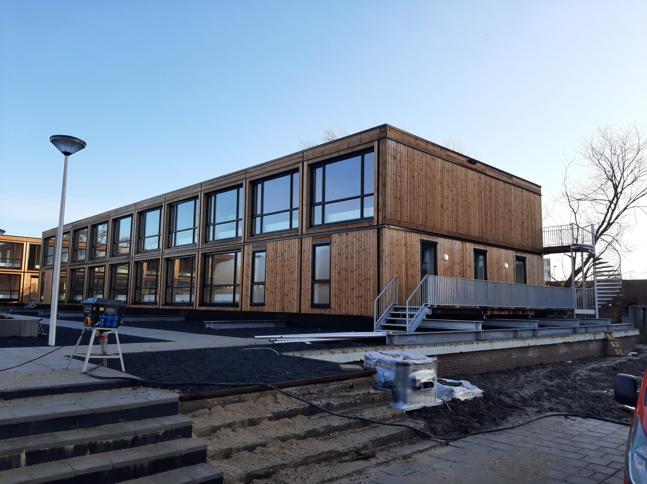 De zijkant van een houten gebouw met een trappetje naar het grind met stoeptegel pad
