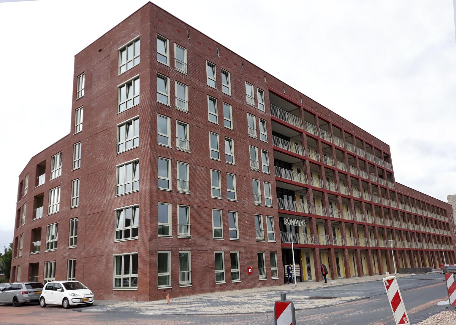 Bakstenen gebouw met veel ramen aan een straatkant