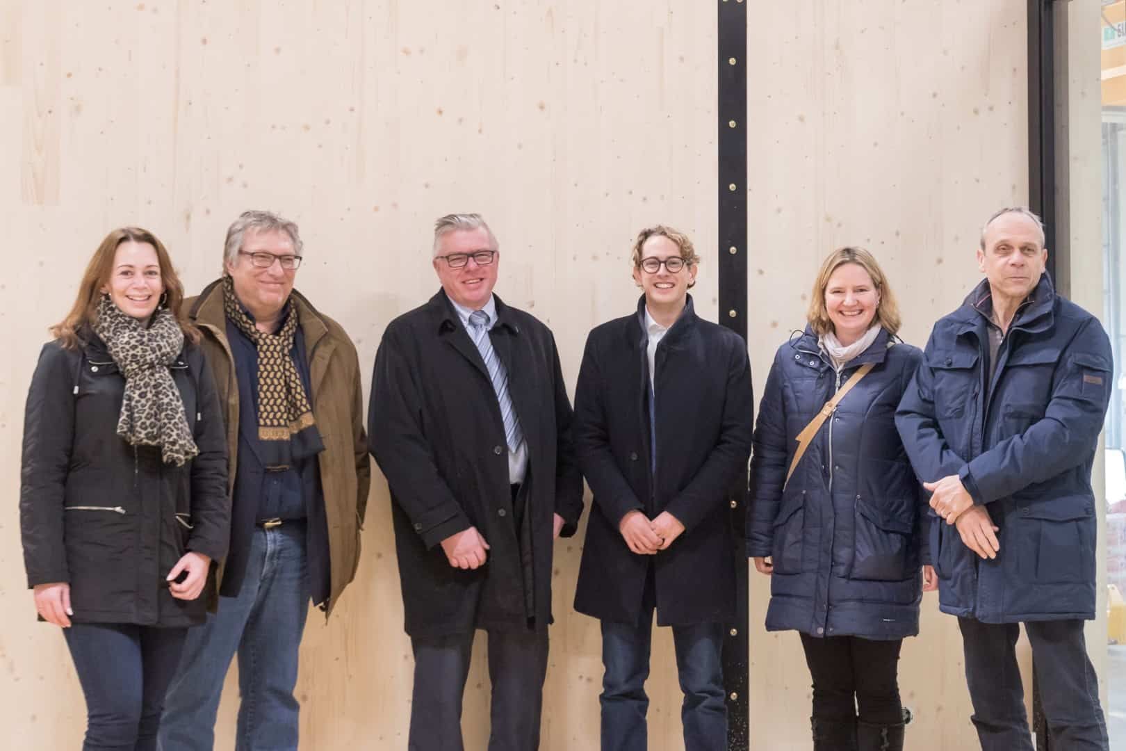 Zes mensen staande voor een houten wand van de Finch module