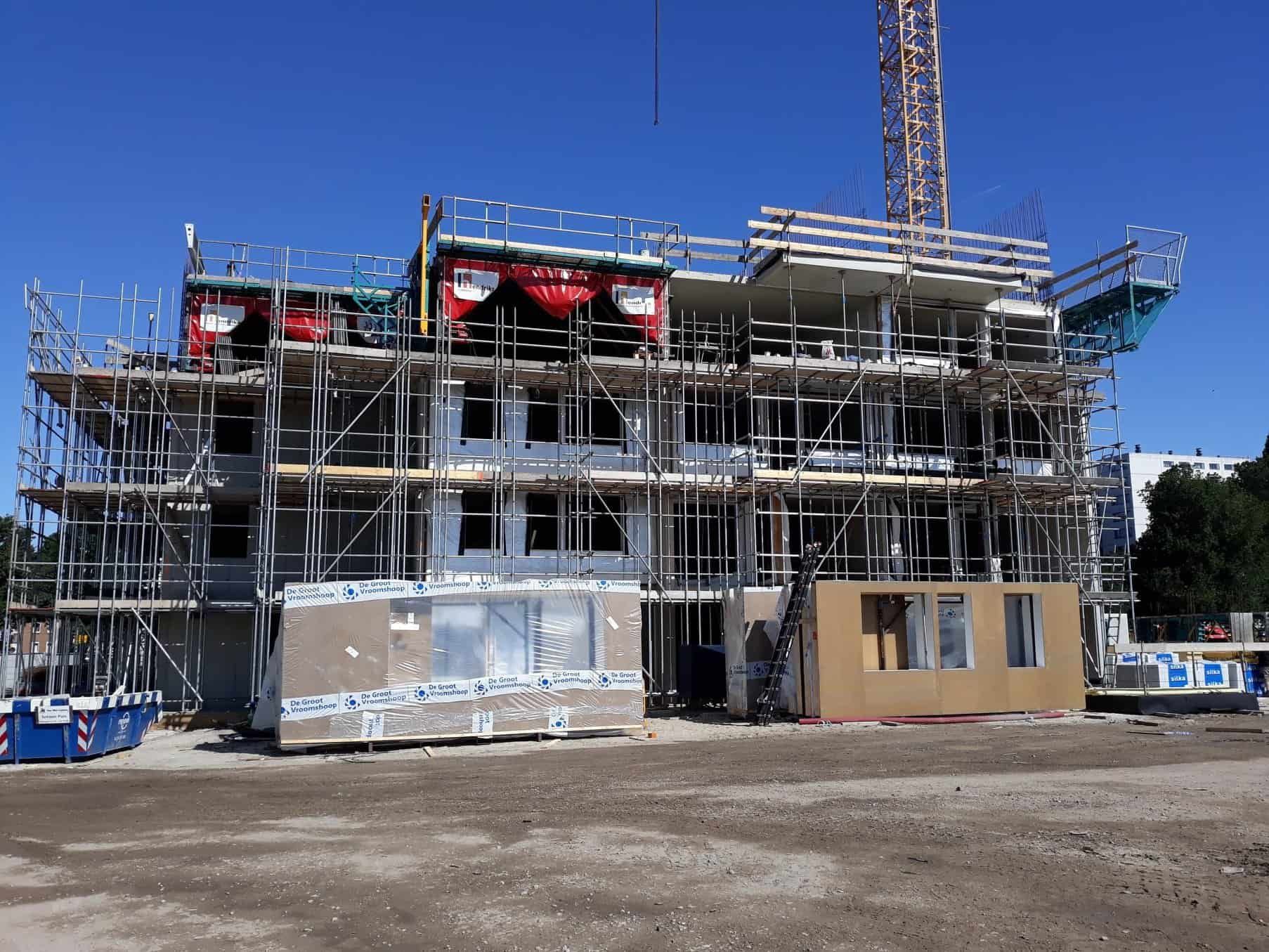 Gebouw in aanbouw met hekken en een hijskraan