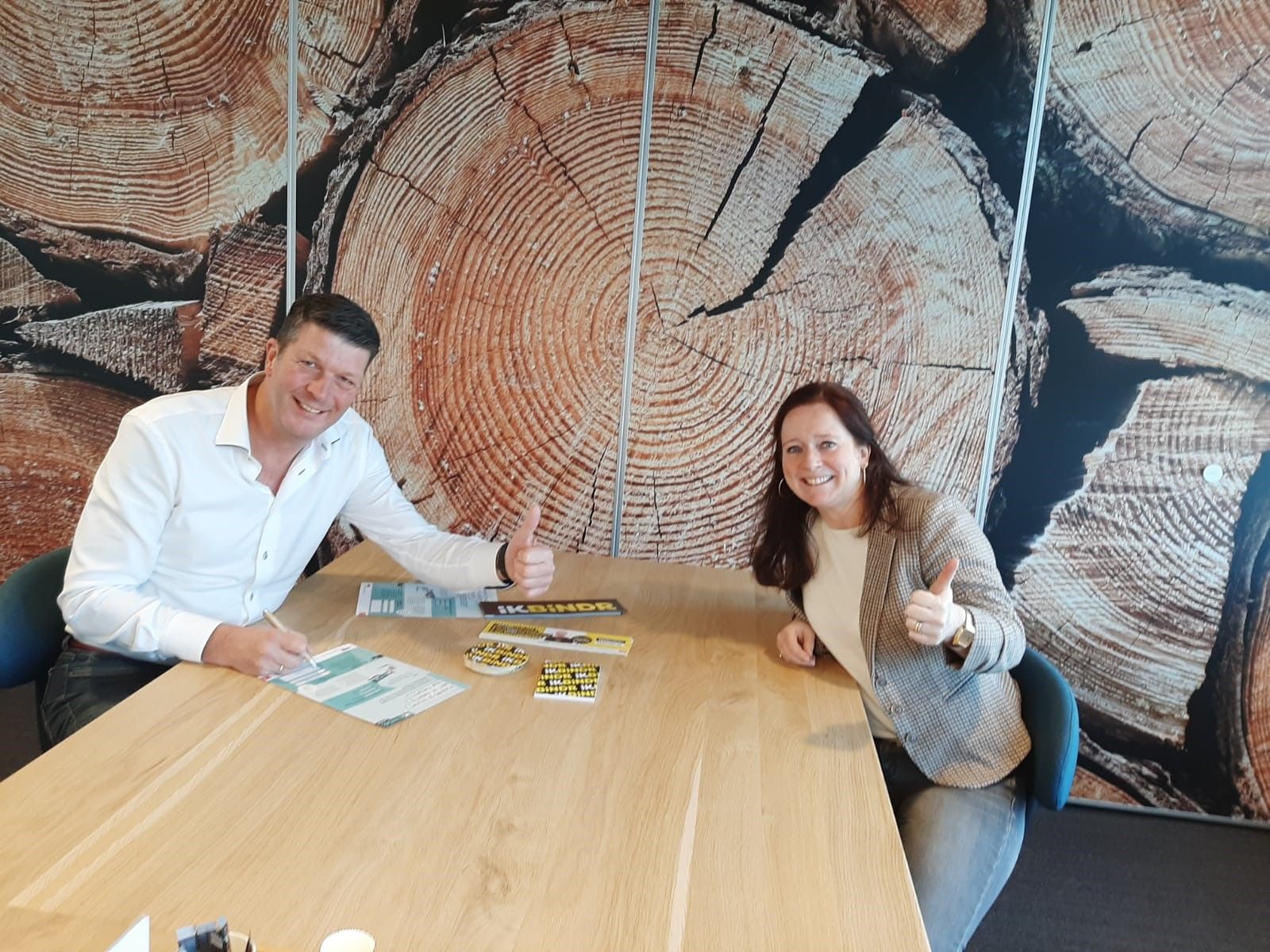 Twee personen tekenen contract aan een houten tafel met behang van hout
