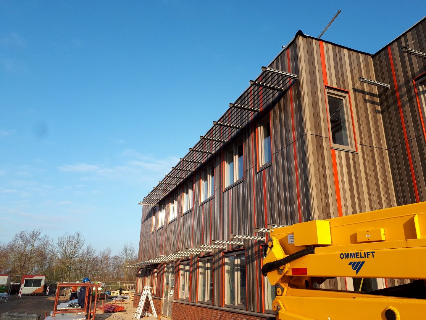 Een vierkant bruin met rode gebouw met een gele kraan ervoor