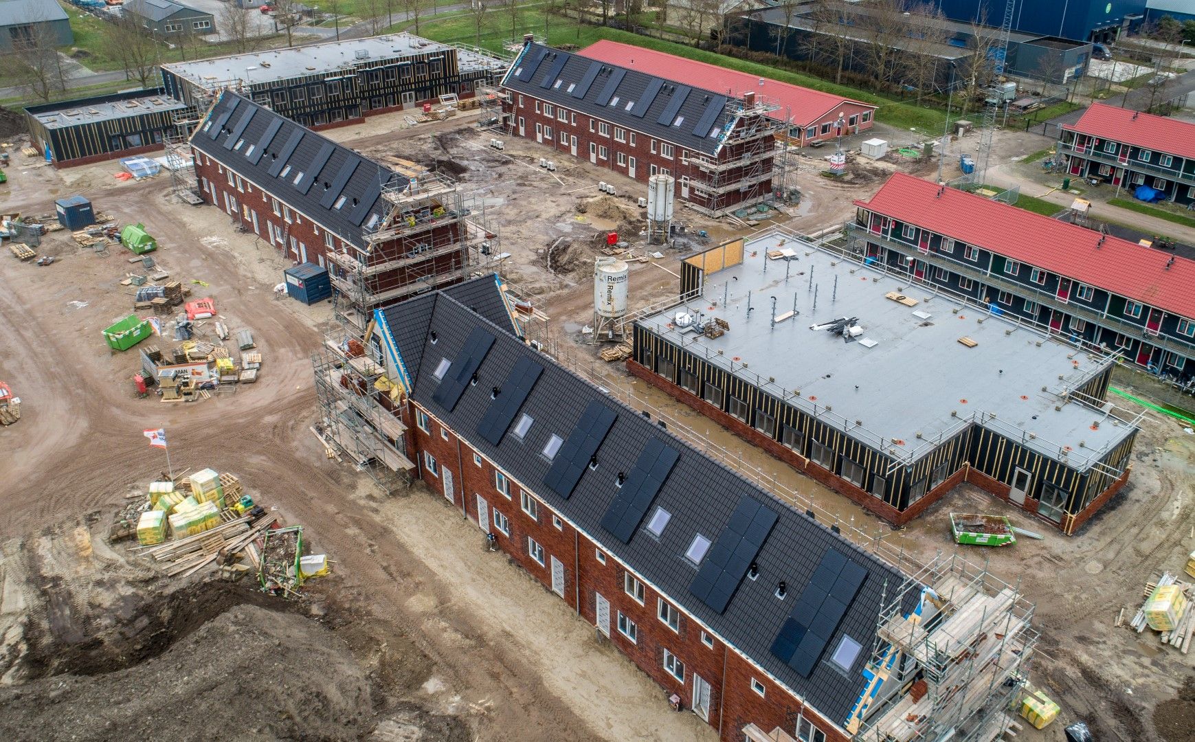 Rode bakstenen rijtjeshuizen met zonnepanelen in een woonwijk in aanbouw