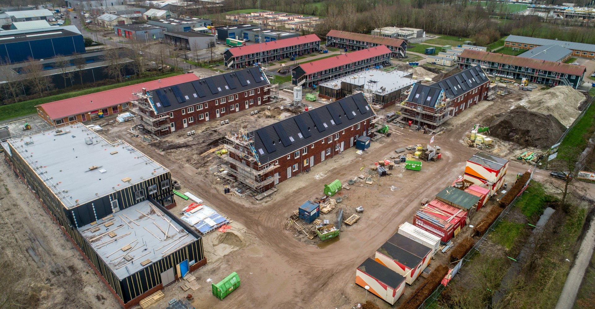 Rode bakstenen rijtjeshuizen met zonnepanelen in aanbouw van bovenaf