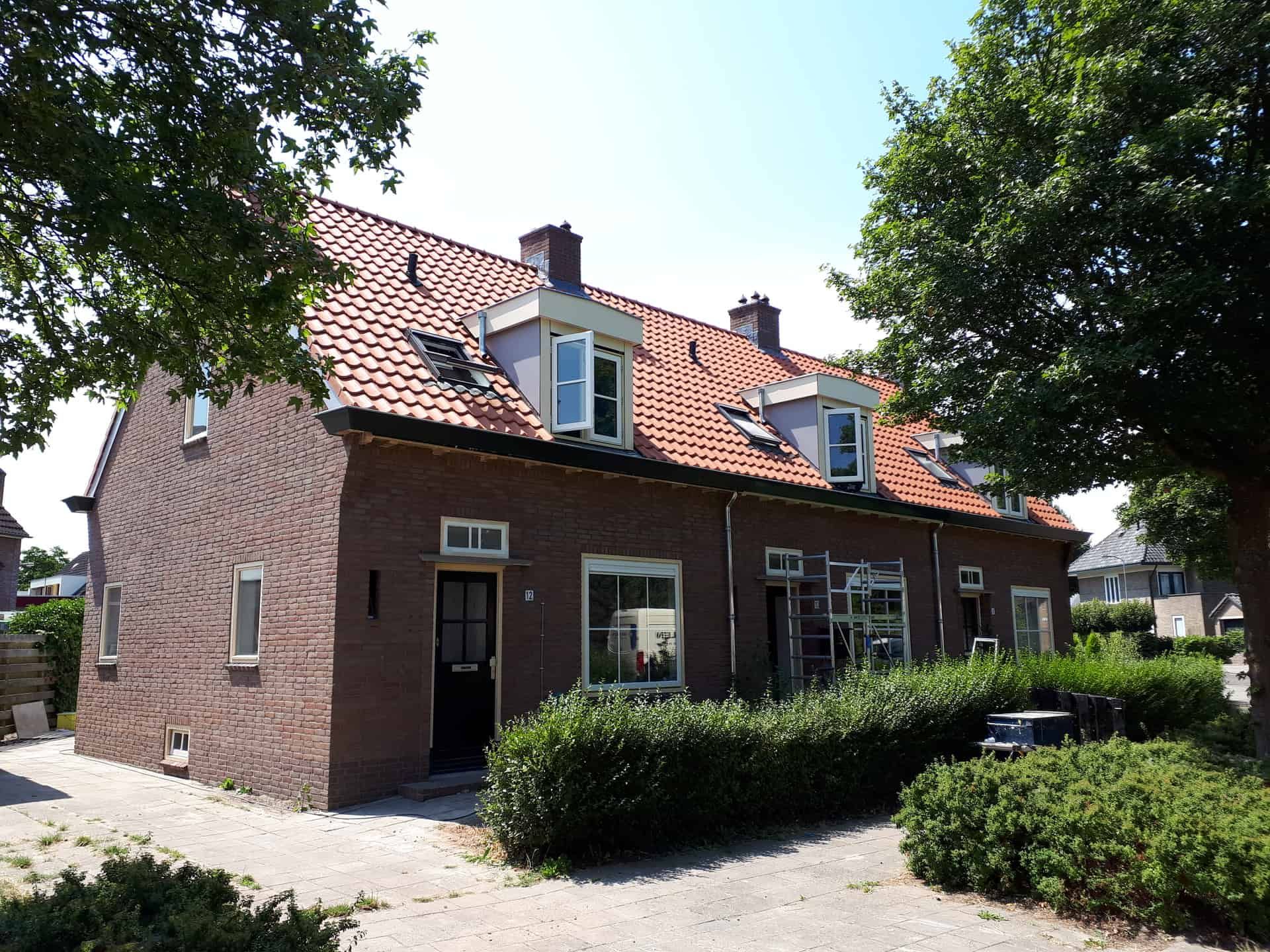 Rijtjeshuizen met bosjes ervoor met nieuwe dakkapellen