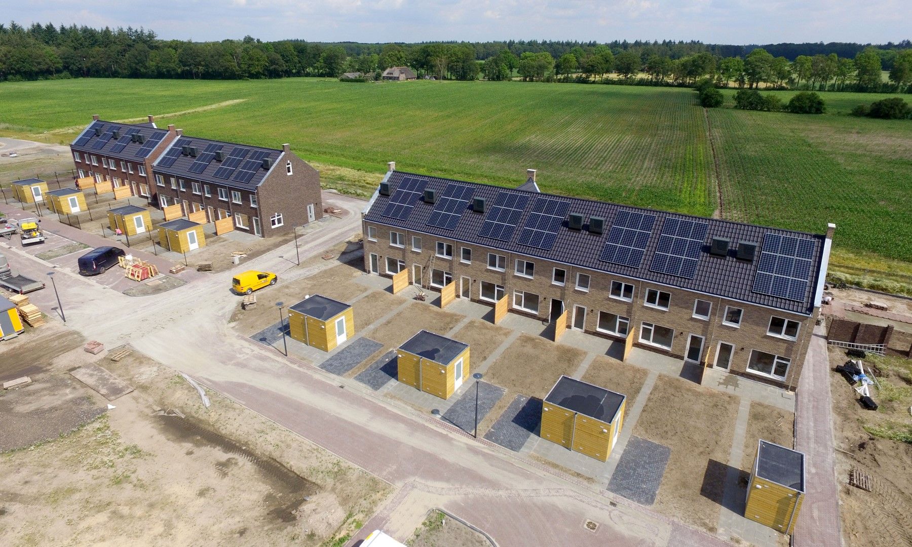 Nieuwbouwwijk met strakke, witte rijtjeshuizen met zwarte daken met zonnepanelen.