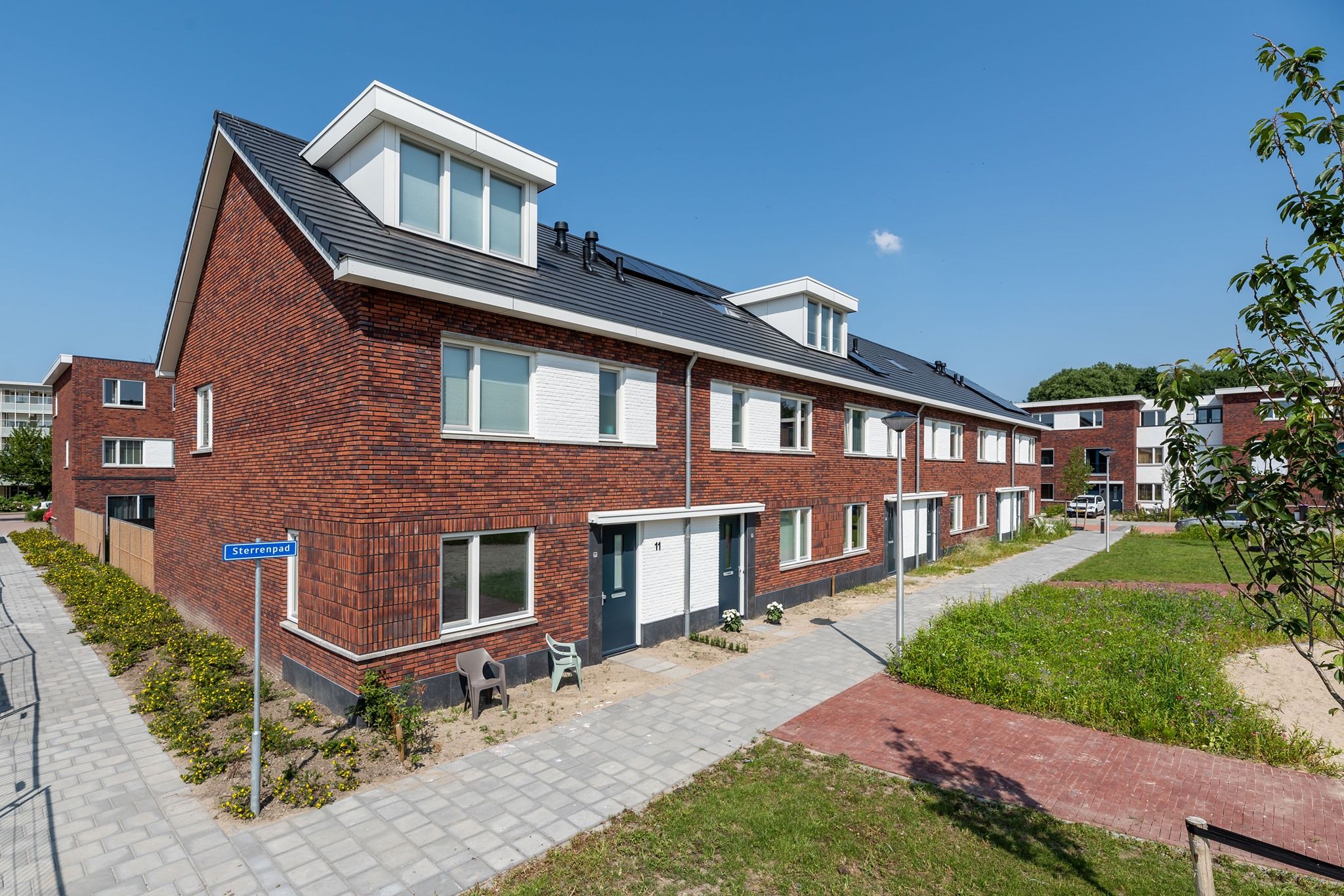 Hoekhuis van een rijtjeshuis met rode bakstenen met een groenstrook ervoor