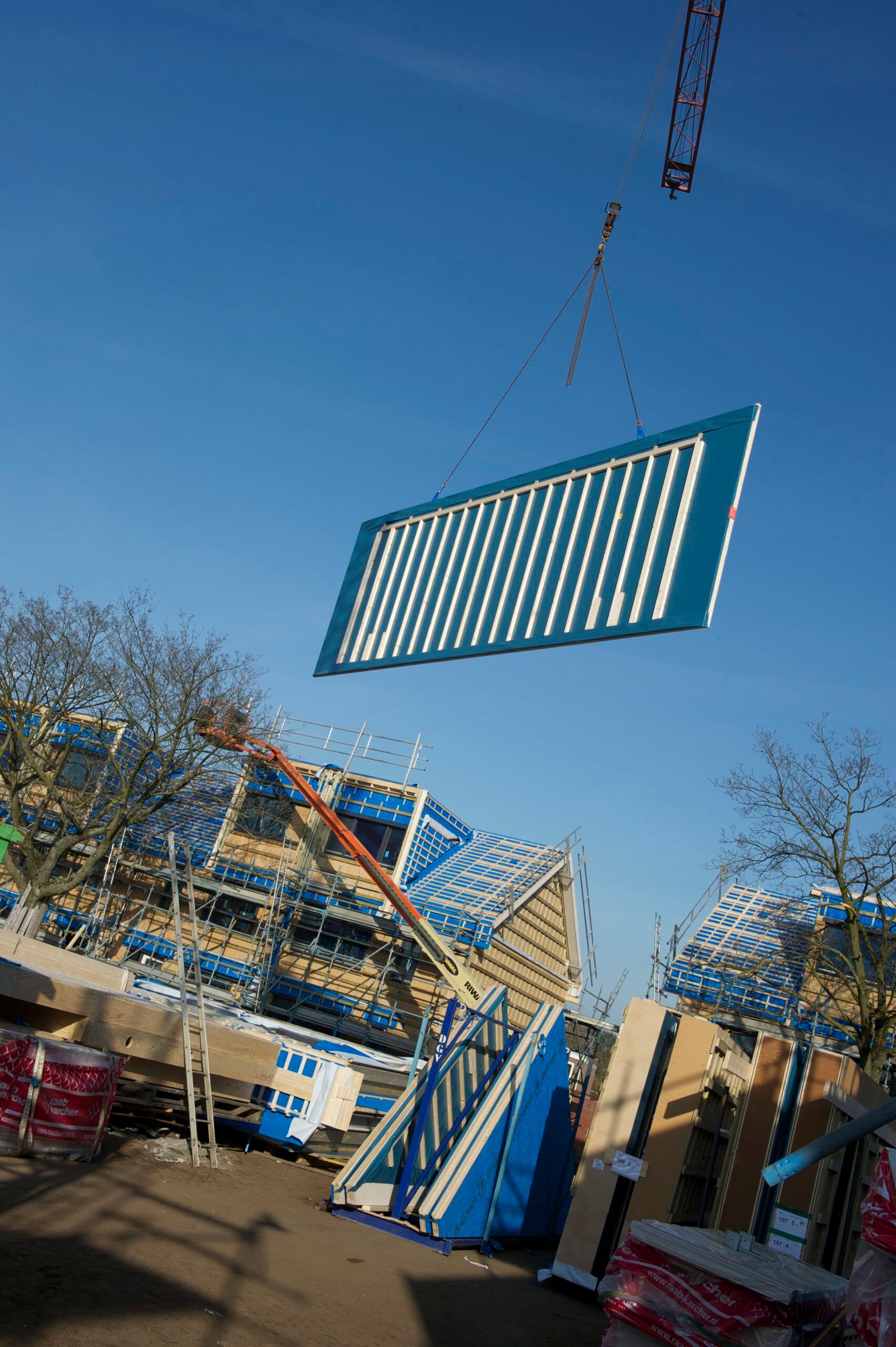 Een blauwe muur met houten balken aan een hijskraan op de bouw