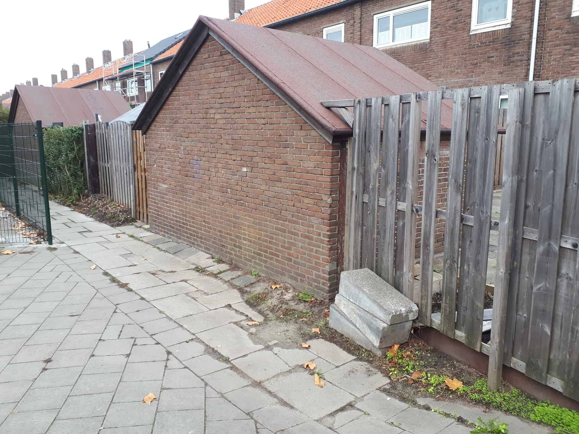 Vervallen bruine houten schutting met oude berging ertussen