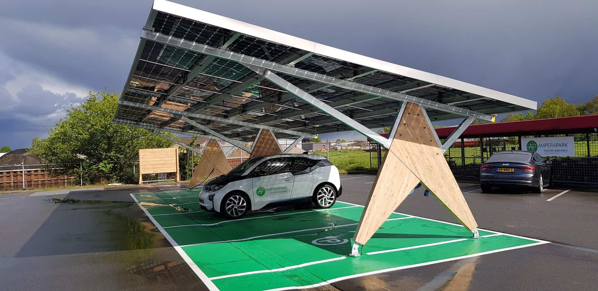 Houten constructie van overkapping met zonnepanelen met een vak van groen asfalt en witte auto