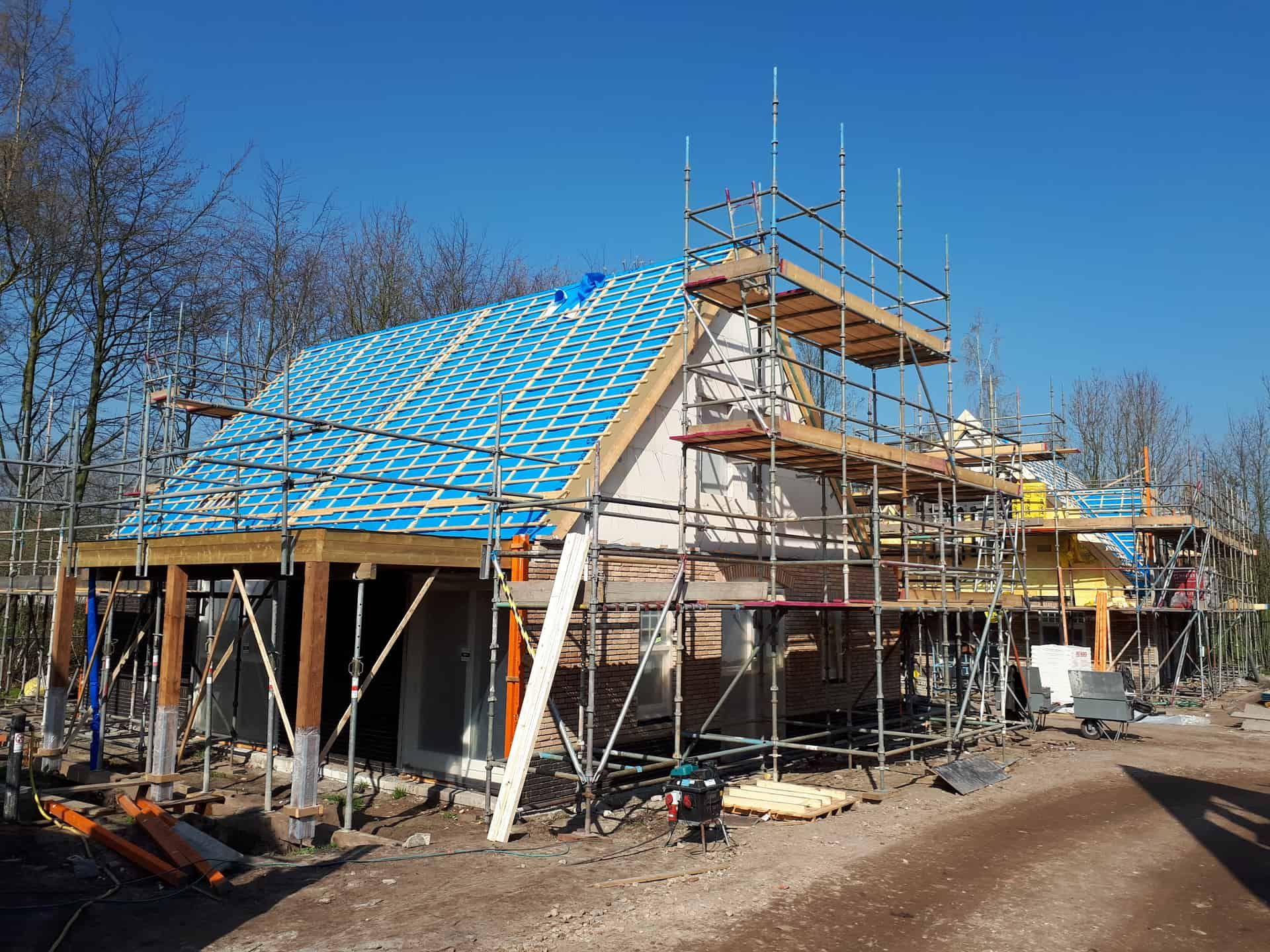 Blauwe prefab daken die recent zijn geplaatst op een wit vakantiehuisje omringd door steigers
