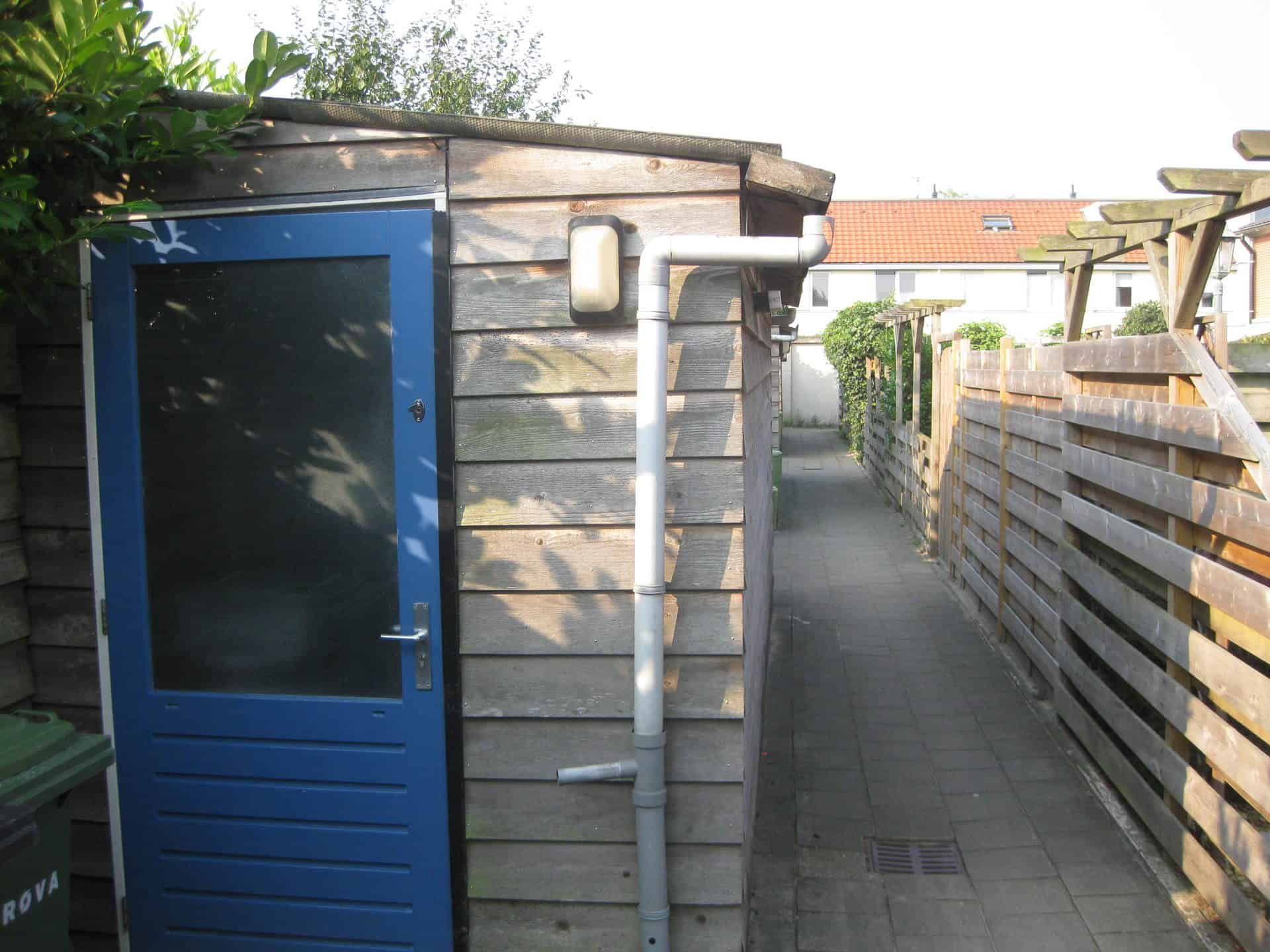 Houten berging met blauwe deur in een steegje