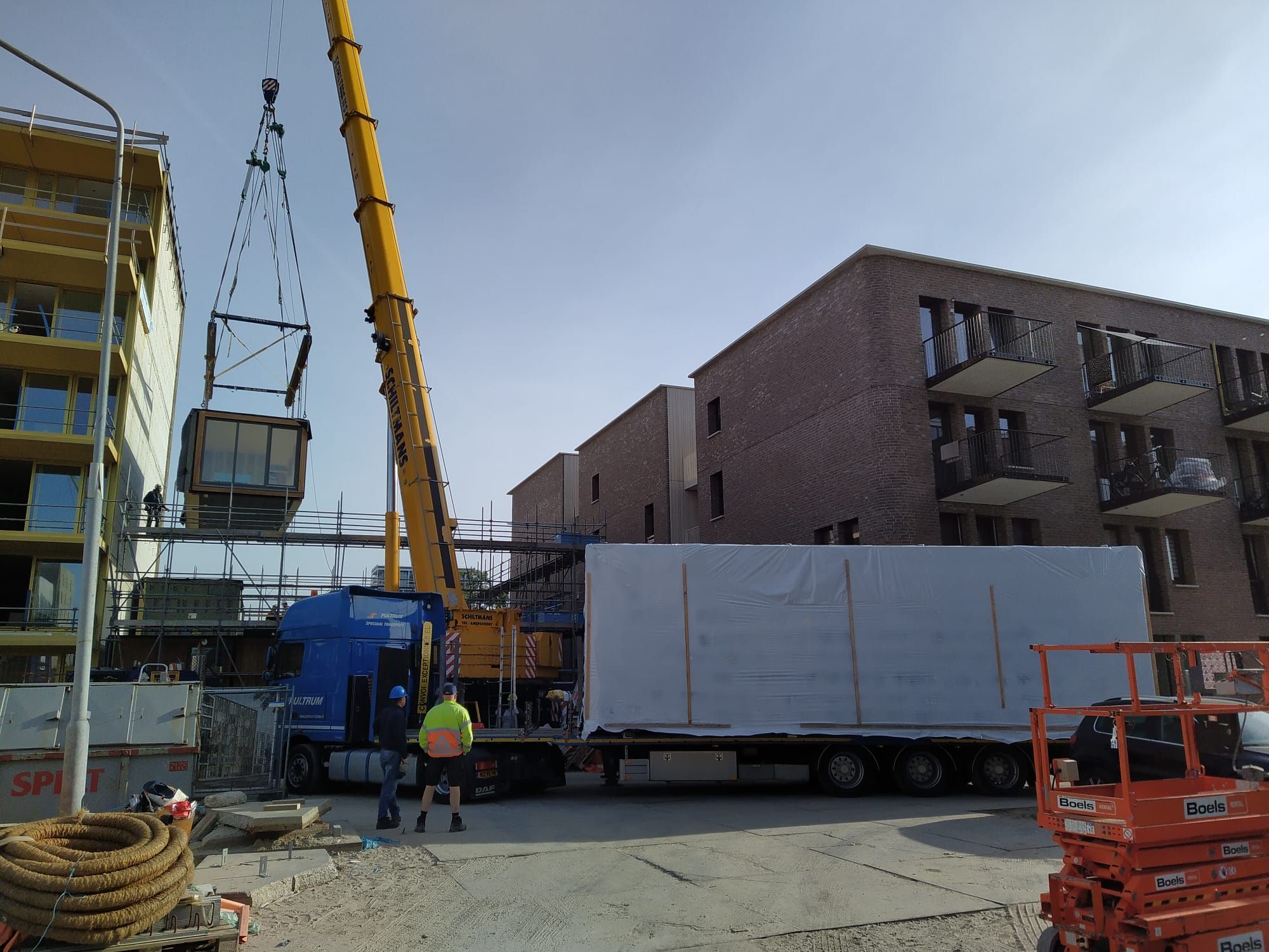Houten woonmodule in de lucht gehezen op een bouwplaats