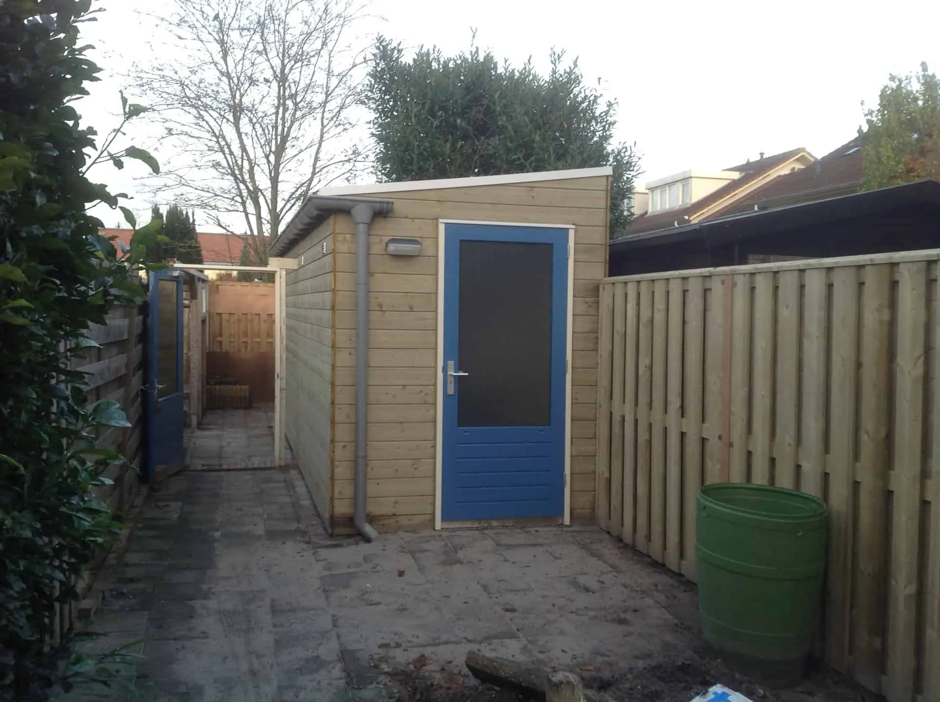 Berging houtkleur met blauwe deur in achtertuin