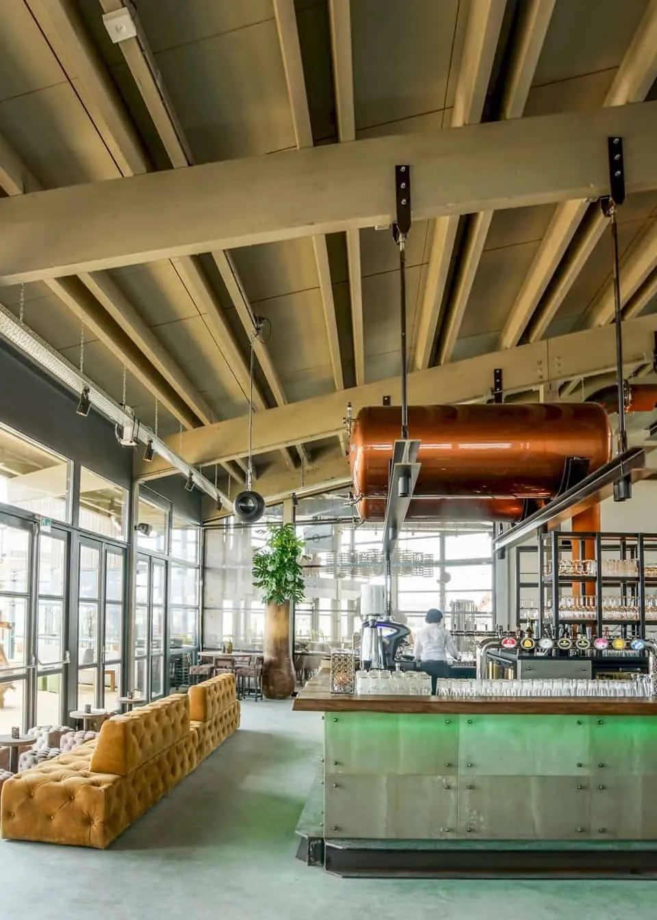 Industrieel restaurant met betonnen en houten bar en okergele bank
