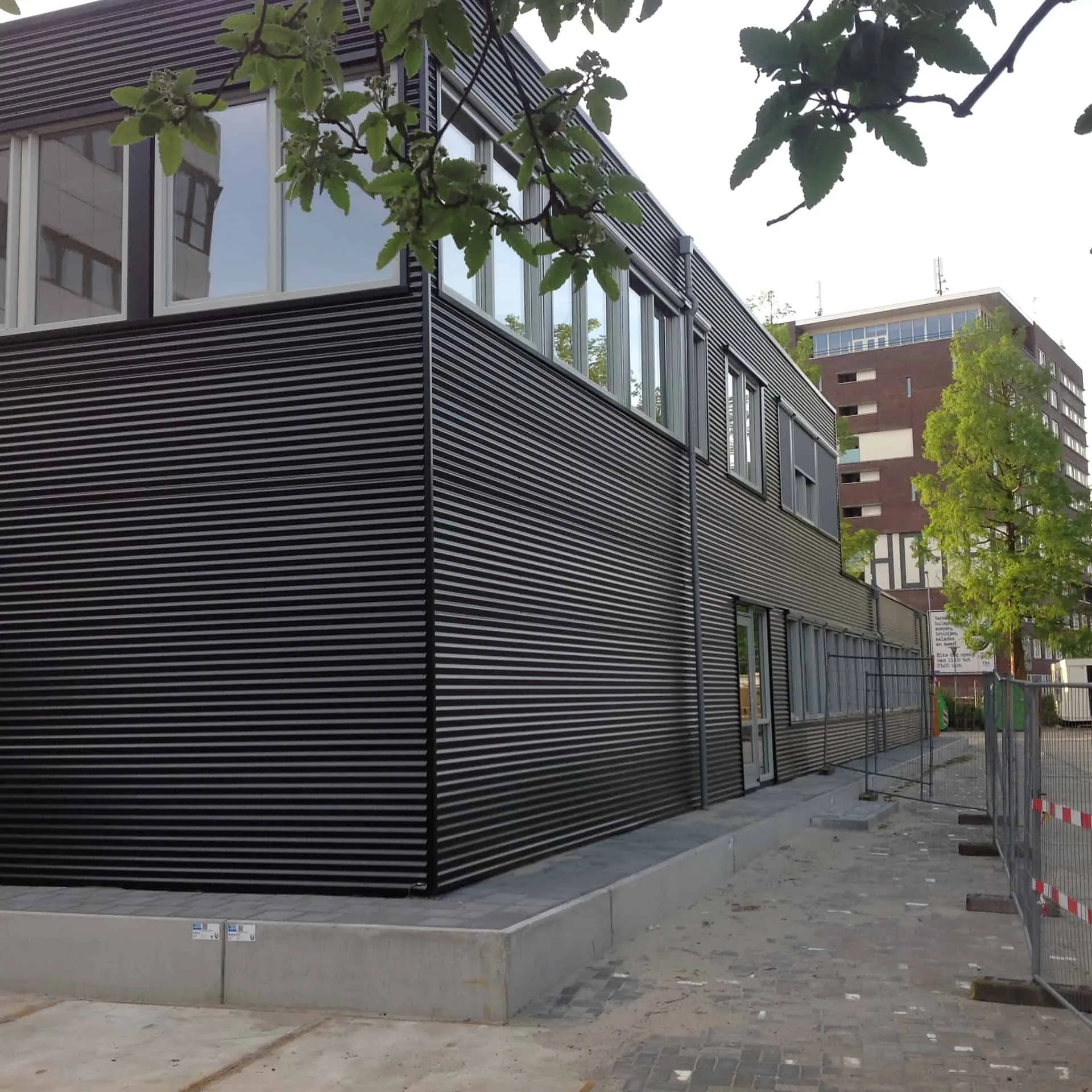 De hoek van het zwarte gebouw van het UMCG met bomen