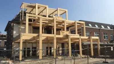 Aanbouw met houten constructie aan een huis met hekken ervoor